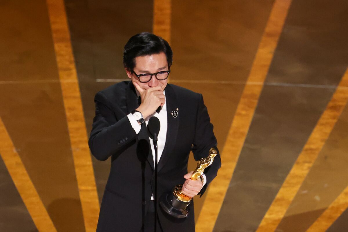 A man onstage accepting an Oscars