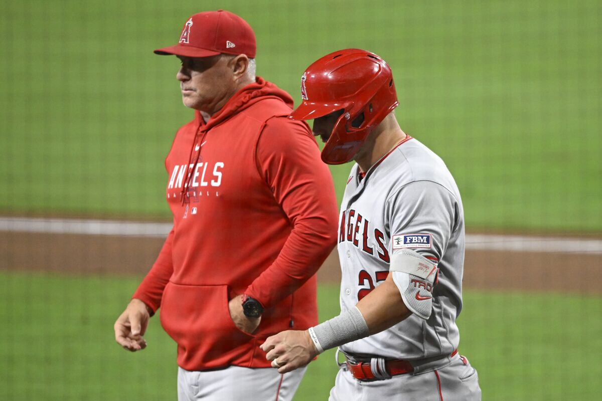 Angels' Mike Trout walks next to manager Phil Nevin as he leaves the game.