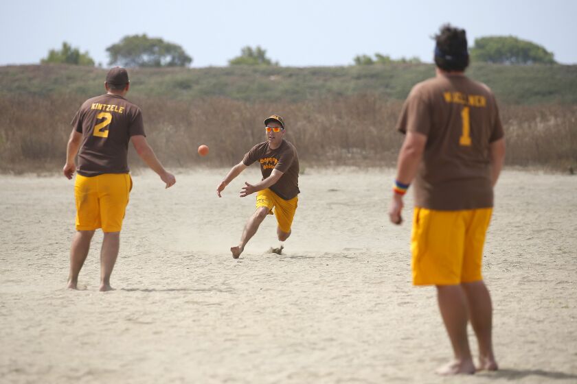 Bobby Taft, center, tries to make a catch while playing for the Tony Gwynn Bobbleheads in the open division during the 66th Annual World Championship Over-The-Line on Fiesta Island in San Diego on July 14, 2019. Teammates Geno Kintzele, left, and Luke Wuellner look on. The tournament continues next weekend.