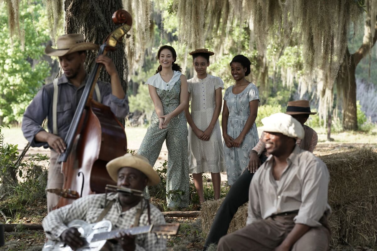 Several young women watch a small group of musicians performing outdoors.