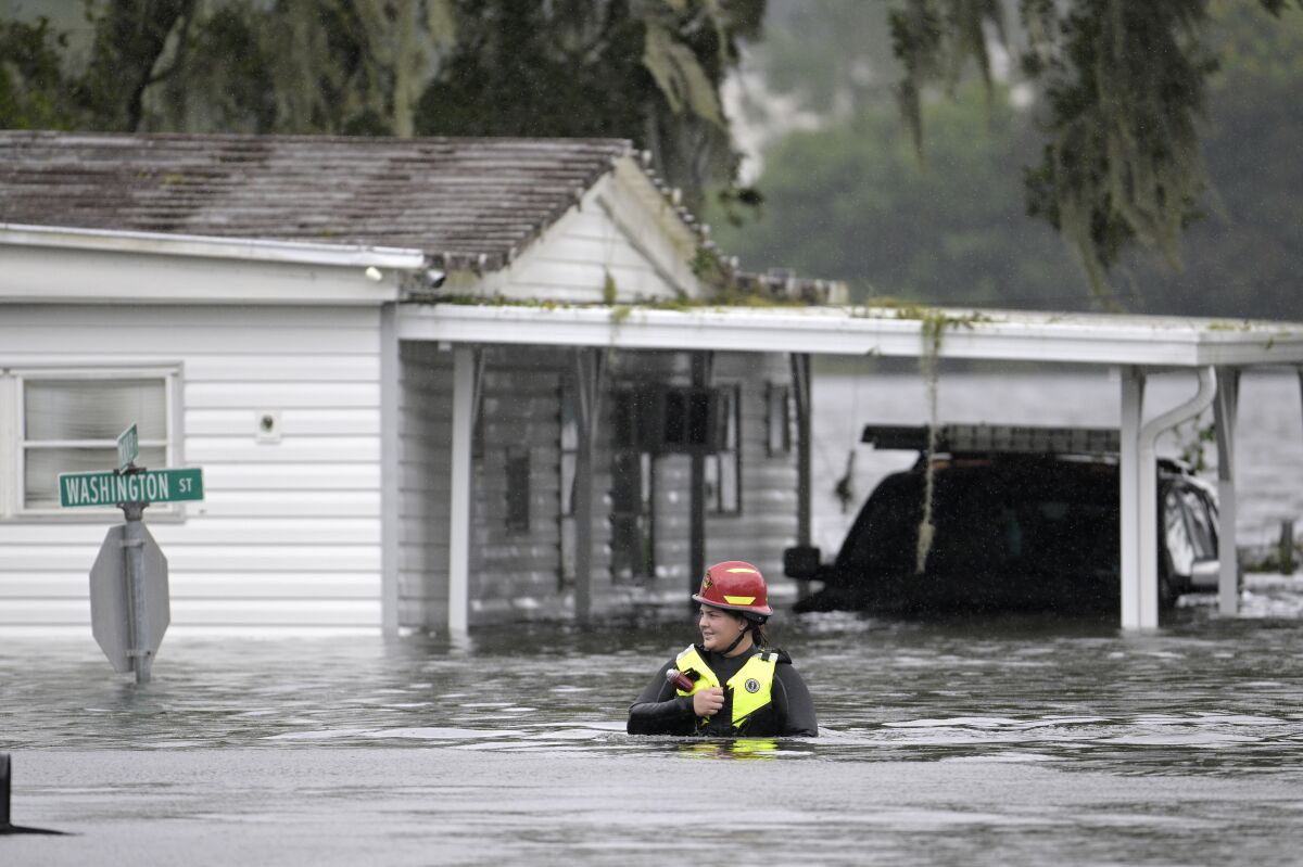 A first responder with Orange County Fire Rescue makes her way through floodwaters looking for residents of a neighborhood needing help in the aftermath of Hurricane Ian, Thursday, Sept. 29, 2022, in Orlando, Fla. (AP Photo/Phelan M. Ebenhack)