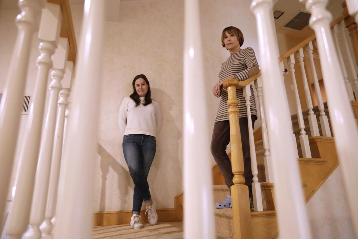Two women pose on the stairs of a home