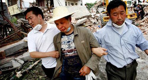 Tan Keren, 50, center, is led away by relatives after his wife's body was found at the site of their home, which was destroyed in the earthquake.
