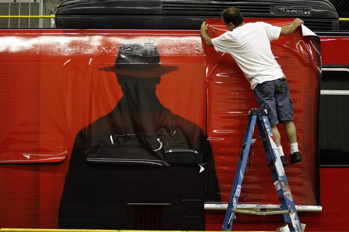 Farzad Parvizi, of Pixel imaging Media, puts on self adhesive transit vinyl as he wraps a trolley car with an advertising wrap for "The Exorcist" television show.