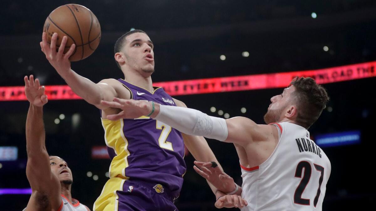 Los Angeles Lakers guard Lonzo Ball shoots over Portland Trail Blazers guard CJ McCollum, left, and center Jusuf Nurkic.