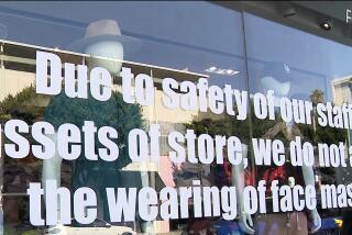 Signage stenciled on the front window of Kitson in Beverly Hills states the store banning masks during its regular business hours because of a string of robberies in the area.