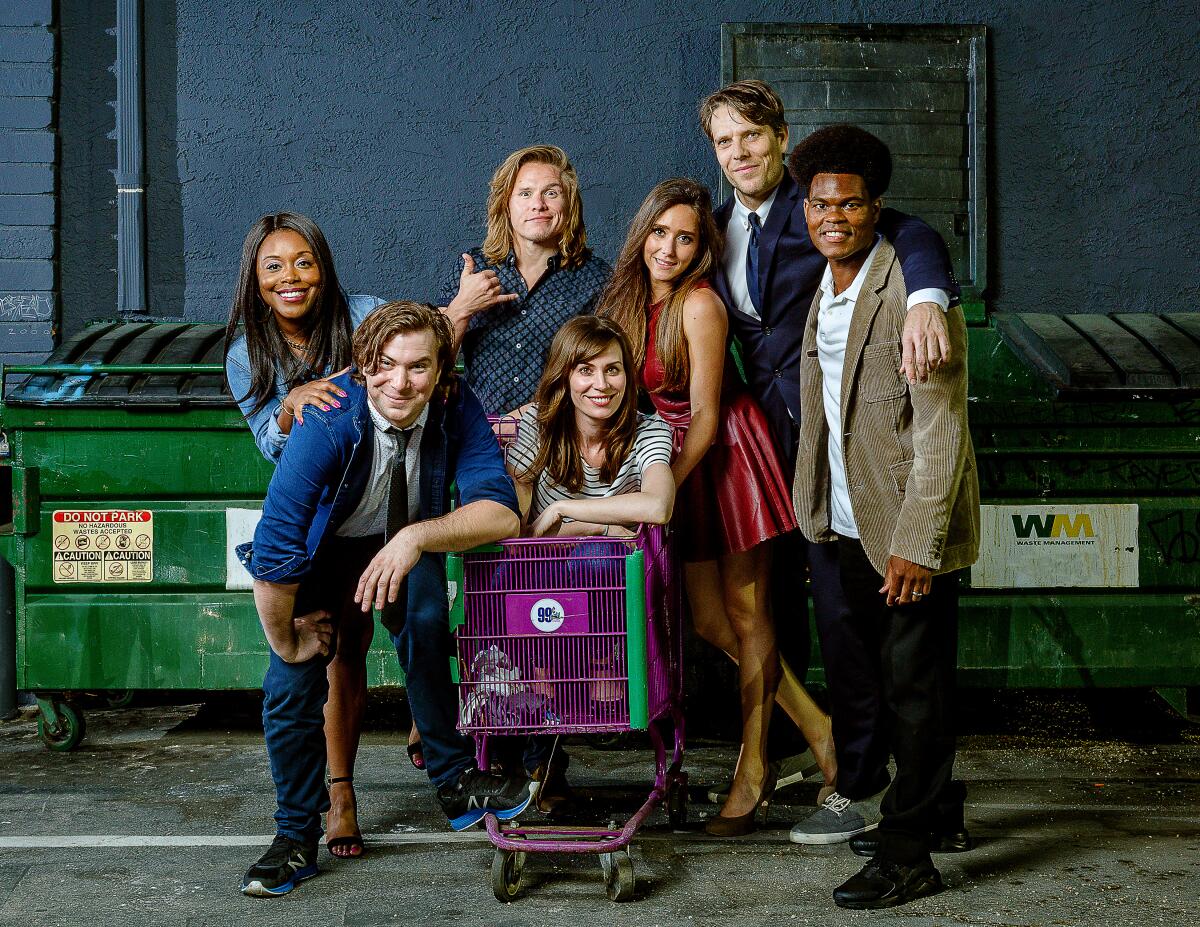 A group of men and women pose for a photo around a purple shopping cart.