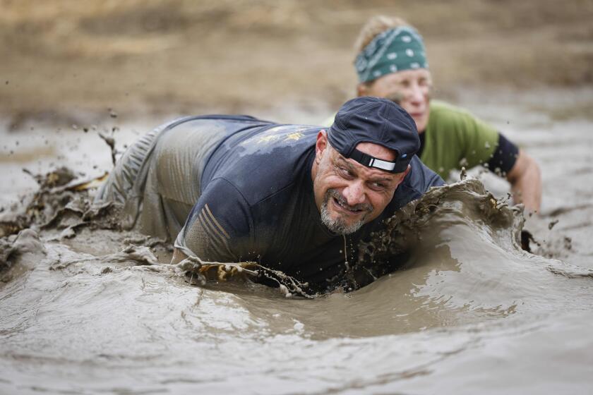 Participants crawl through the final mud pit during the Marine Corps Mud Run.