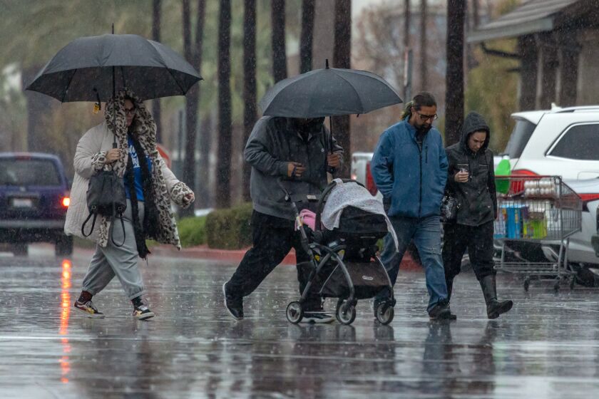 Rancho Cucamonga, CA - January 14: Shoppers in heavy rain rush through a parking lot of a wholesale store Costco on Saturday, Jan. 14, 2023 in Rancho Cucamonga, CA. (Irfan Khan / Los Angeles Times)