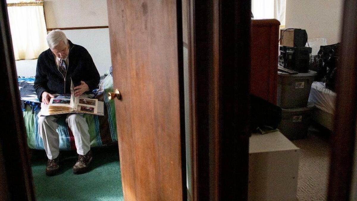 A resident of an assisted living home in Clio, Mich., flips through a photo album in his room in January 2019.