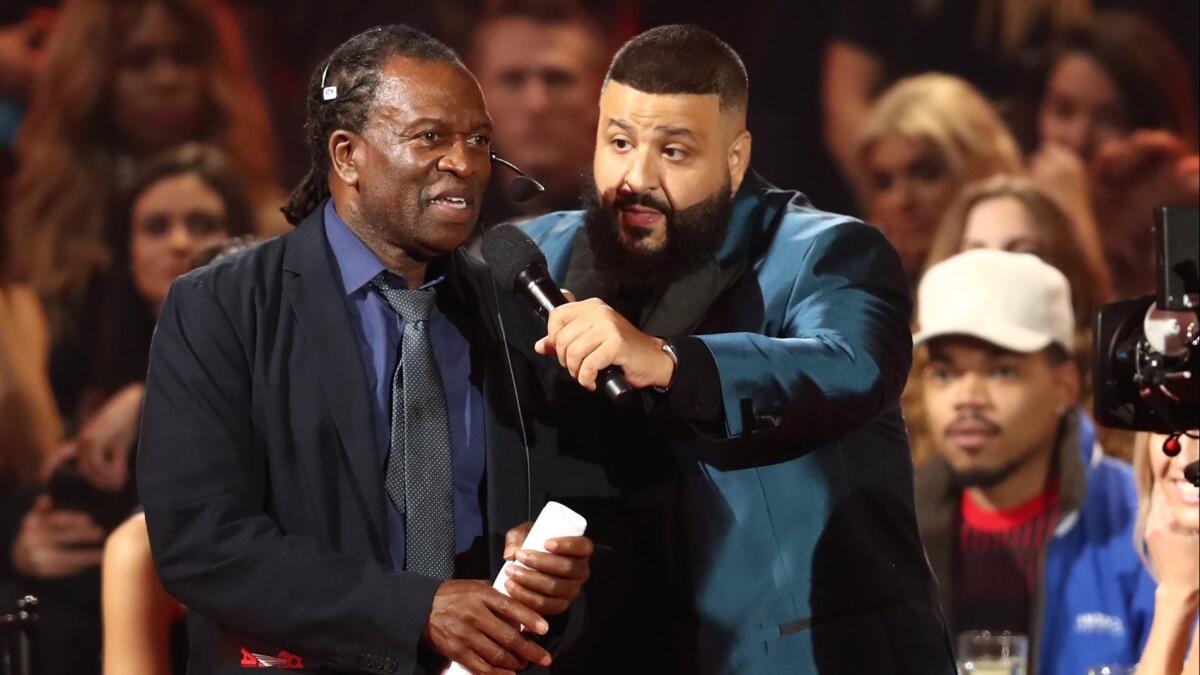 DJ Khaled, right, gets a stagehand to help him as host of Sunday's iHeartRadio Music Awards.