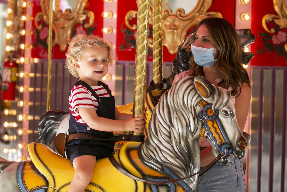 Jacques and Abigail Carrere ride the carousel at South Coast Plaza on Friday, June 25.