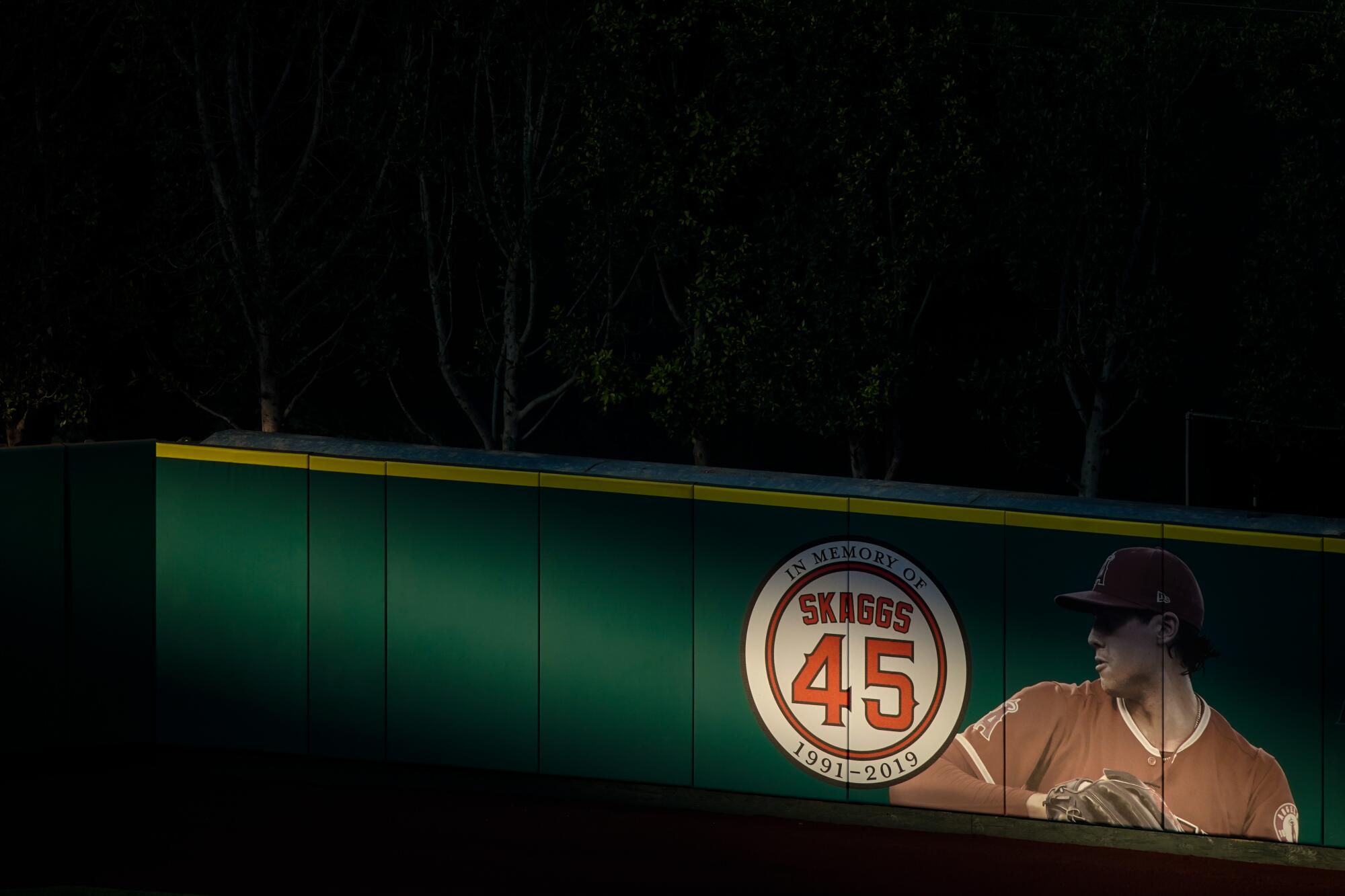 A ray of light is cast sidelong against a green outfield wall with a profile shot of Tyler Skaggs beside his name and number