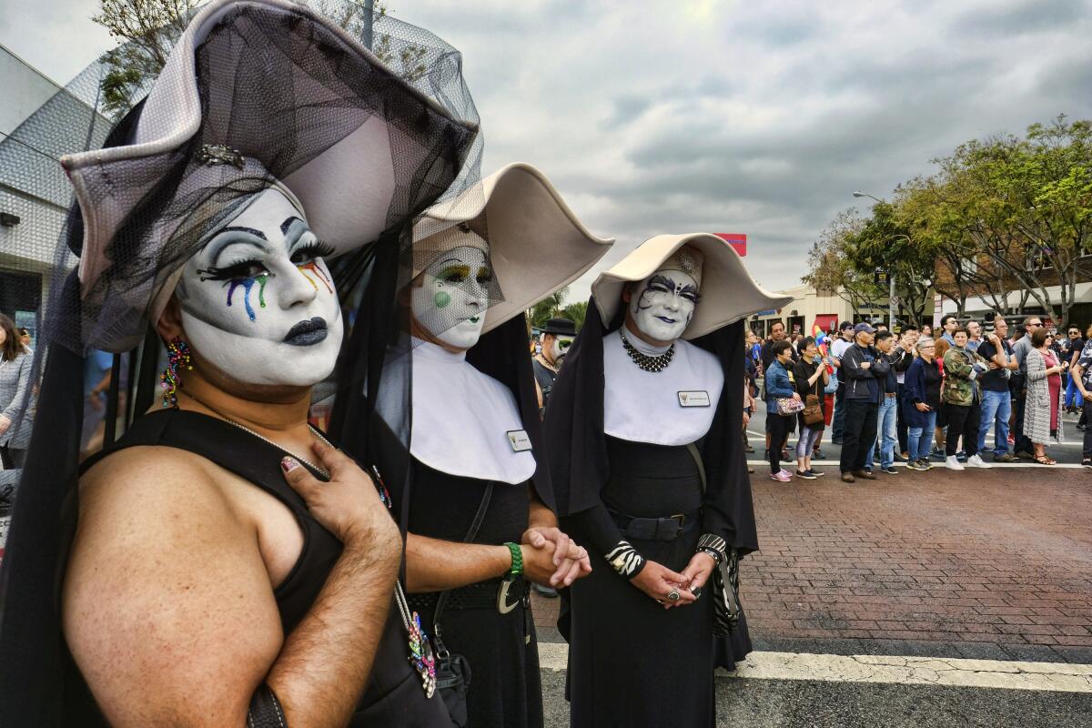 Three people in white makeup dressed up as nuns.