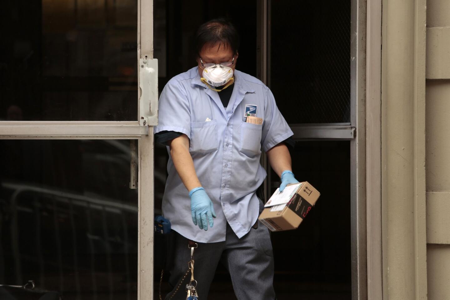 Keven Ngo wears a mask and gloves to deliver the mail at Dr. Craig Spencer's apartment building. He did not wear it on the rest of his route.