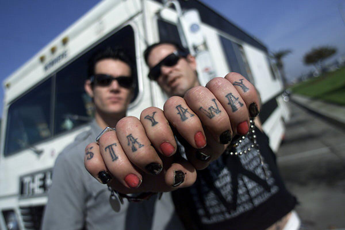 The Hunns guitarist Rob Milucky, left, and Duane Peters pose in front of their touring RV in Newport Beach. Peters has been sentenced after pleading guilty to a domestic violence charge.
