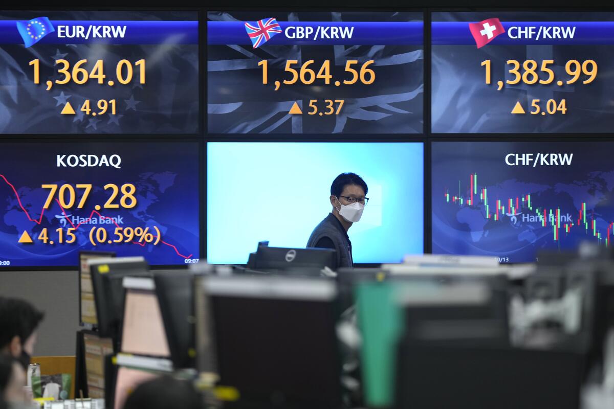 A man walks by the screens showing the foreign exchange rates.