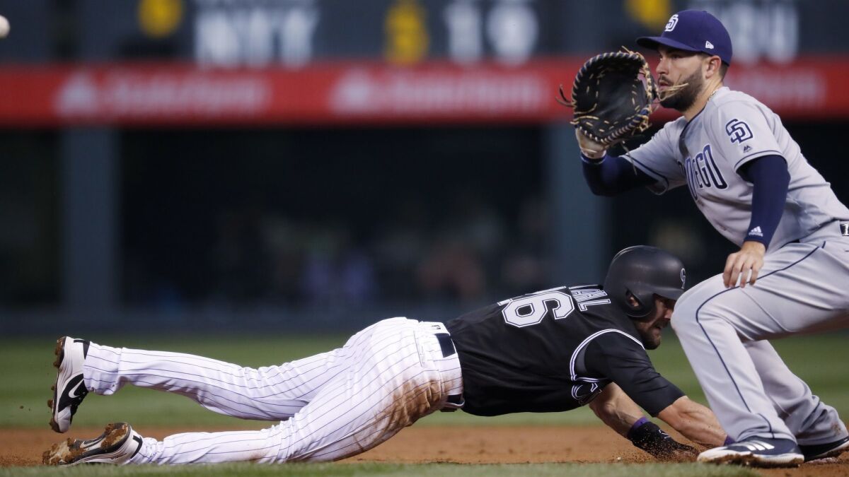 Colorado Rockies' David Dahl, left, dives back into first base as San Diego Padres first baseman Eric Hosmer fields a pickoff throw in the first inning Monday.