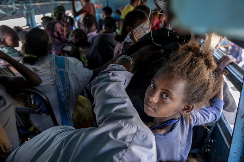 Refugees fleeing the conflict in Ethiopia's Tigray ride a bus headed to a temporary shelter in eastern Sudan on Dec. 1.