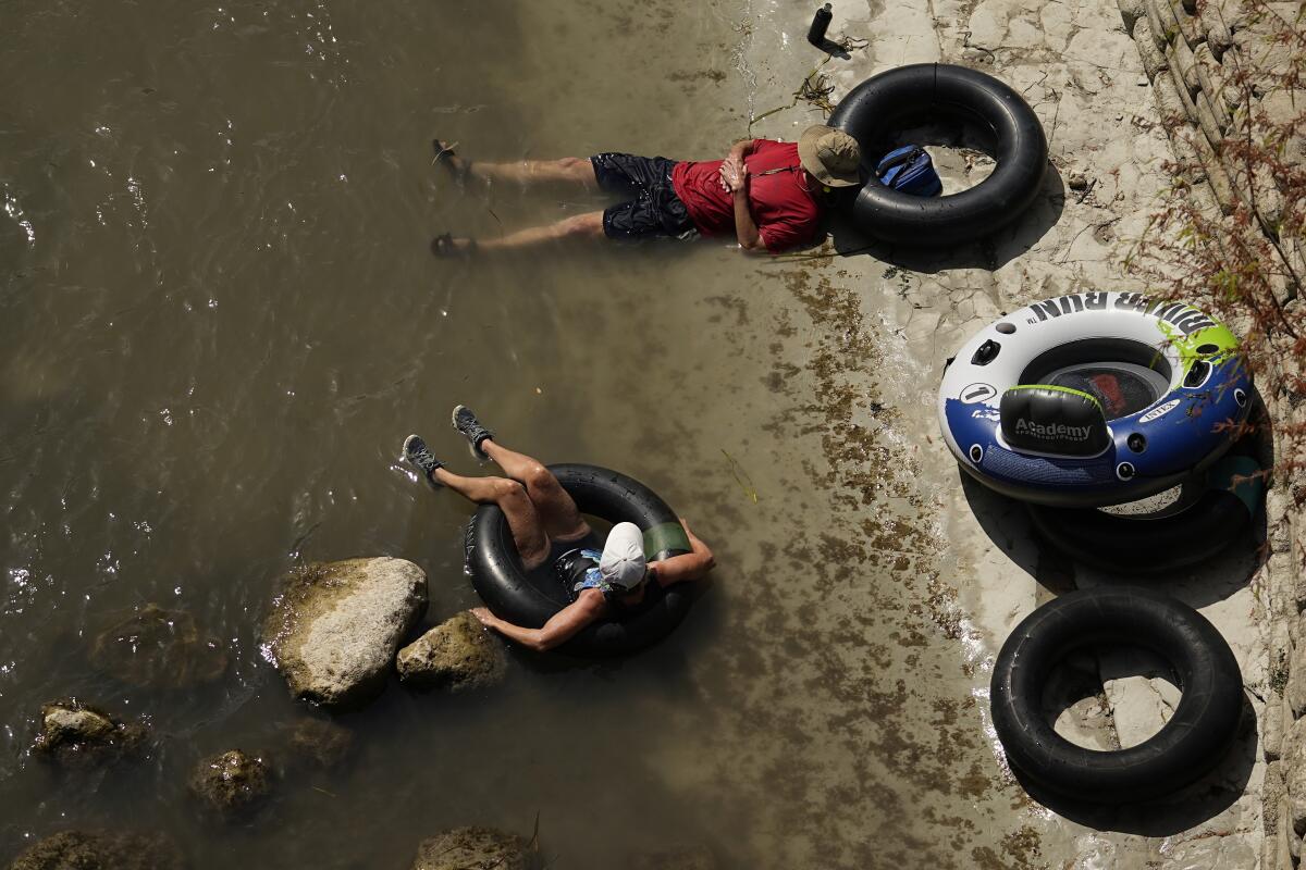 ARCHIVO - Una pareja descansa a orillas del río Comal, el 26 de julio de 2023, en New Braunfels, Texas
