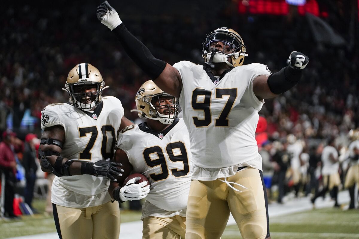 New Orleans Saints' Christian Ringo (70) and Malcom Roach (97) celebrate the fumble recovery by New Orleans Saints defensive tackle Shy Tuttle (99) during the second half of an NFL football game against the Atlanta Falcons, Sunday, Jan. 9, 2022, in Atlanta. (AP Photo/Brynn Anderson)