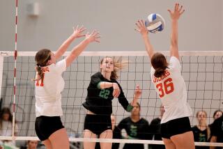 Mira Costa High’s Audrey Flanagan hits through Huntington Beach blockers Haylee LaFontaine and Kylie Leopard on Saturday.