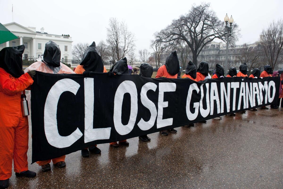 Protestors wear orange detainee jumpsuits and black hoods as they hold a banner calling for the closing of the US detention center at Guantanamo naval base in Cuba in front of the White House in Washington on January 11, 2014.