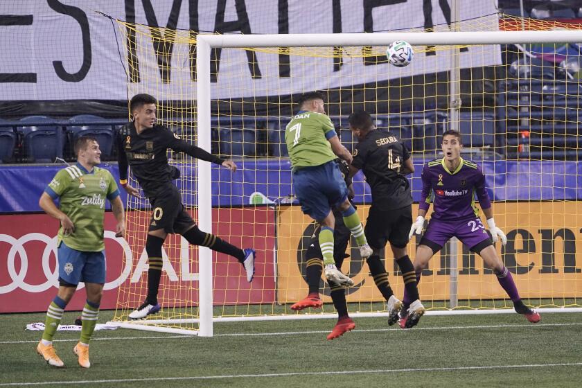 Los Angeles FC goalkeeper Pablo Sisniega, right, watches as Seattle Sounders midfielder Cristian Roldan (7) and LAFC defender Eddie Segura (4) vie for a head ball during the second half of an MLS soccer match Friday, Sept. 18, 2020, in Seattle. The Sounders won 3-0. (AP Photo/Ted S. Warren)
