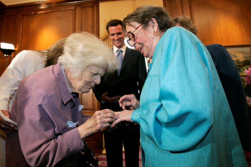 FILE - In this June 16, 2008, file photo, Del Martin, left, places a ring on her partner Phyllis Lyon, right, during their wedding ceremony officiated by then-San Francisco Mayor Gavin Newsom, center, at City Hall in San Francisco. Pioneering gay rights activist Lyon, who was among the first same-sex couples to marry in California when it became legal to do so, has died at her San Francisco home. Lyon died at age 95 of natural causes Thursday, April 9, 2020. (AP Photo/Marcio Jose Sanchez, File)