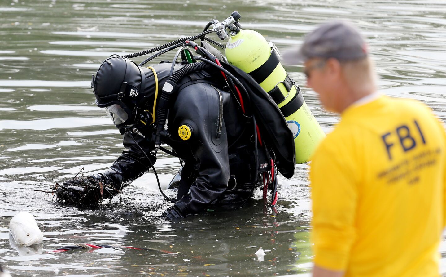 An FBI dive team searches a lake near the Inland Regional Center in connection with last week's terrorist attack.