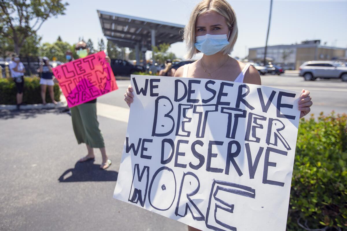 Newport Harbor High School student Summer Nedelman, right, and her mother, Renee, left, hold signs in protest of the Newport-Mesa Unified School District's decision to not hold in-person graduation ceremonies this year because of the COVID-19 pandemic.