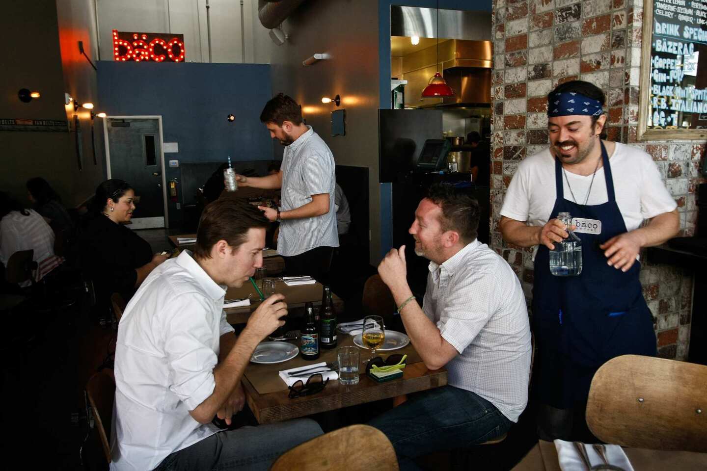 Alex Pauley, right, waits on customers inside Baco Mercat. The menu offers several small plates.