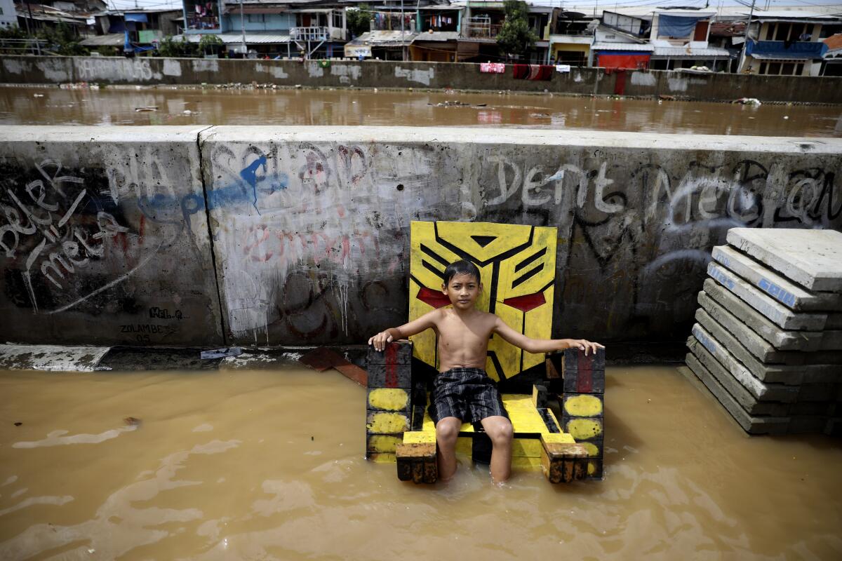 A young boy sits on a chair in a flooded neighborhood in Jakarta, Indonesia, on Thursday.
