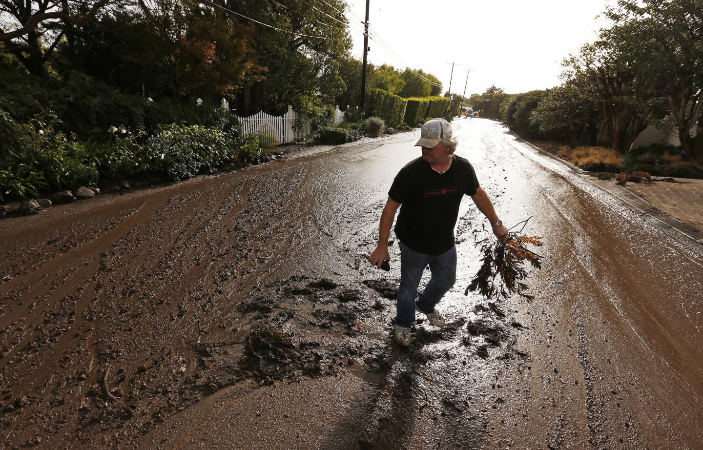 Troy Miller trudges through the mud near his home in western Malibu on Thursday afternoon. Rain triggered mudflows in hills loosened by the Woolsey fire.