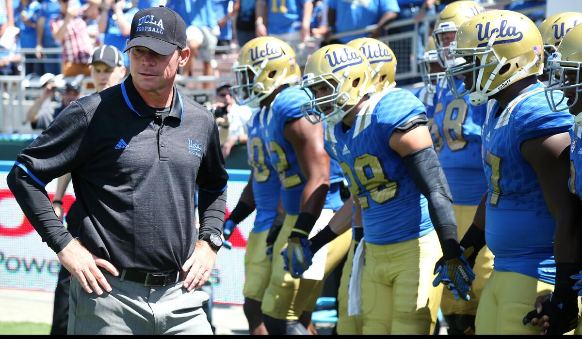 UCLA head coach Jim Mora stands with his team before they take the field against the Virginia Cavaliers at the Rose Bowl on Saturday.