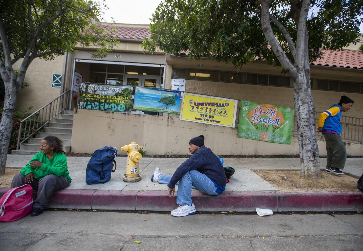 Tyrone Dixon, 53, center, waits with fellow homeless people outside the Echo Park Community Center.