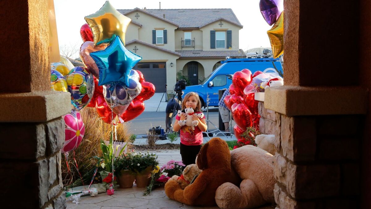 Neighbor Rilee Unger, 3, plays with a toy after dropping off a couple of herteddy bears on the porch of a home where police arrested David and Louise Turpin.