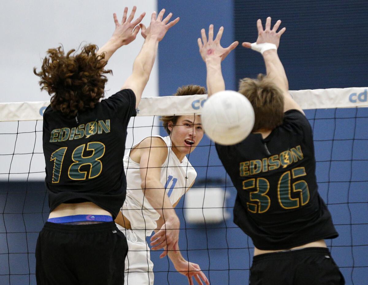 Corona del Mar's Sterling Foley (11) rips a kill past the blocks of Edison's Owen Banner (18) and CJ Addison. 