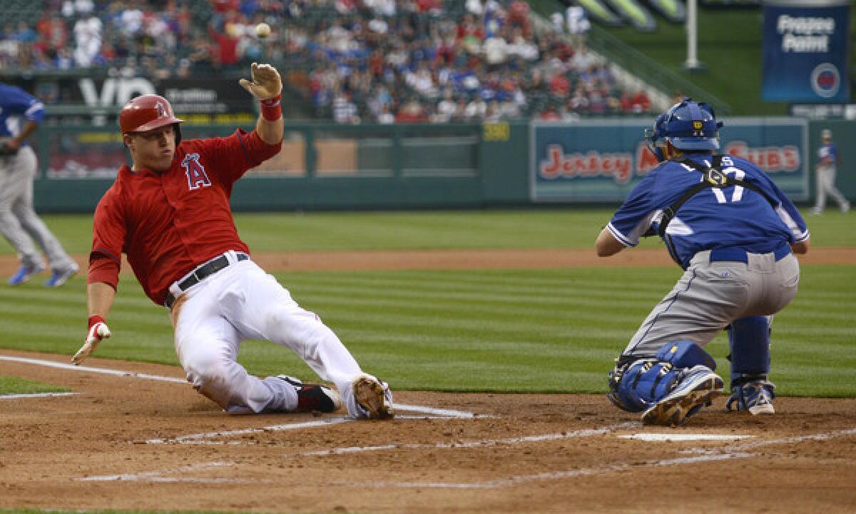 Angels outfielder Mike Trout, left, slides safely past Dodgers catcher A.J. Ellis to score a run during the Angels' 6-2 exhibition win Saturday at Angel Stadium.
