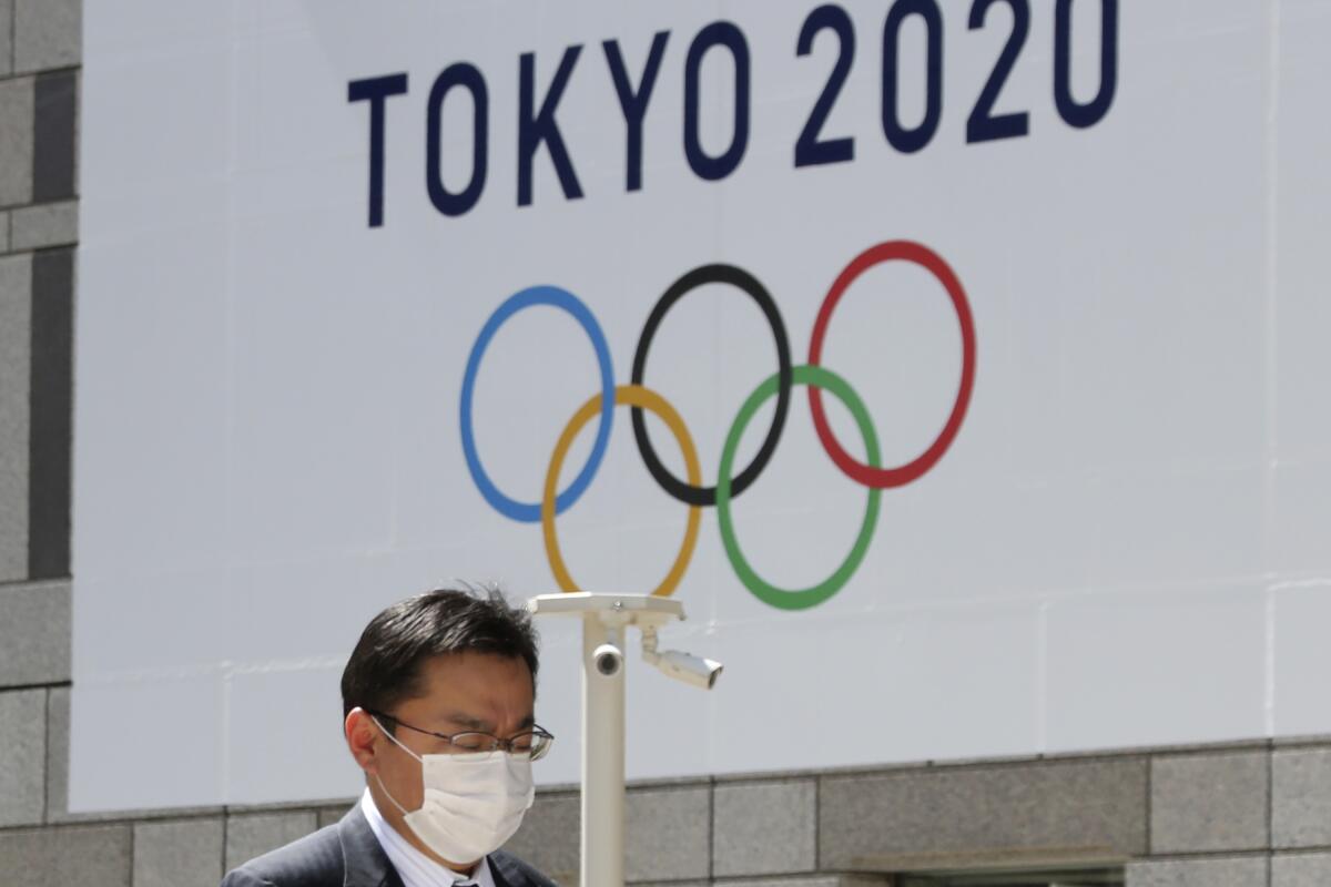 A man walks past a banner of an Olympics logo in Tokyo on March 25. 