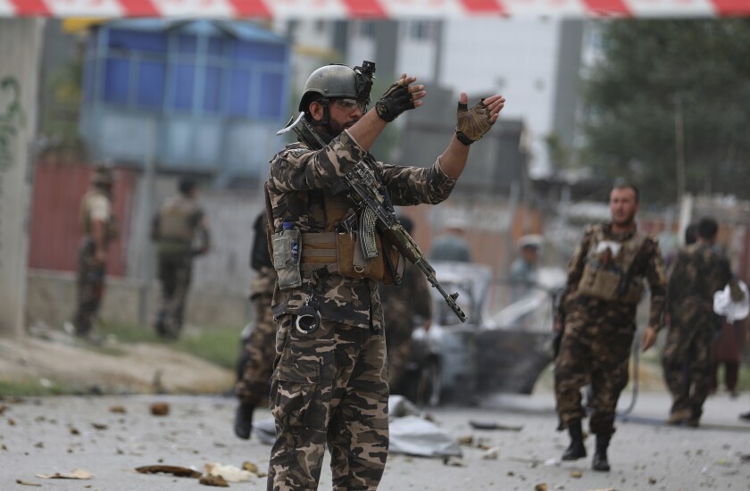 A solider holds his hands up amid rubble and other soldiers in the background