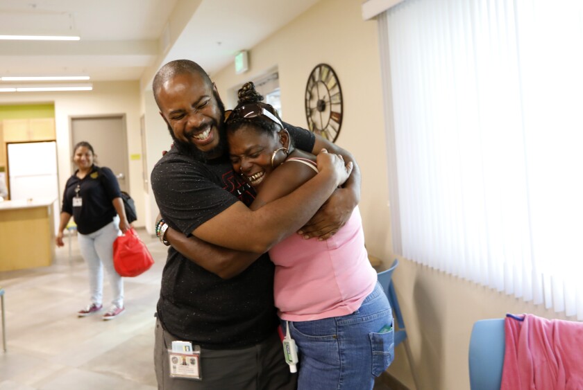 Outreach worker Geoffrey Goosby hugs Big Mama in the community room just after she saw her  new apartment in Los Angeles.
