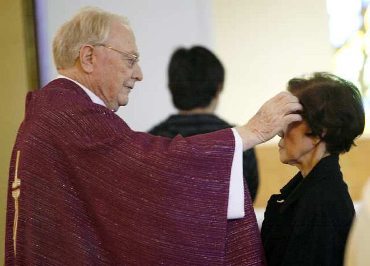 Father Thomas Doyle applies ashes to the forehead of a parishioner at the conclusion of a service on the first day of Lent at the St. James Catholic Church in La Crescenta on Thursday, February 22, 2012.