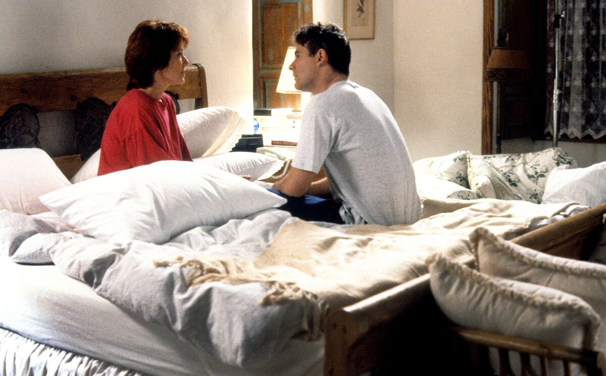 Mary McDonnell and Kevin Kline sit talking, facing each other, in an unmade bed.