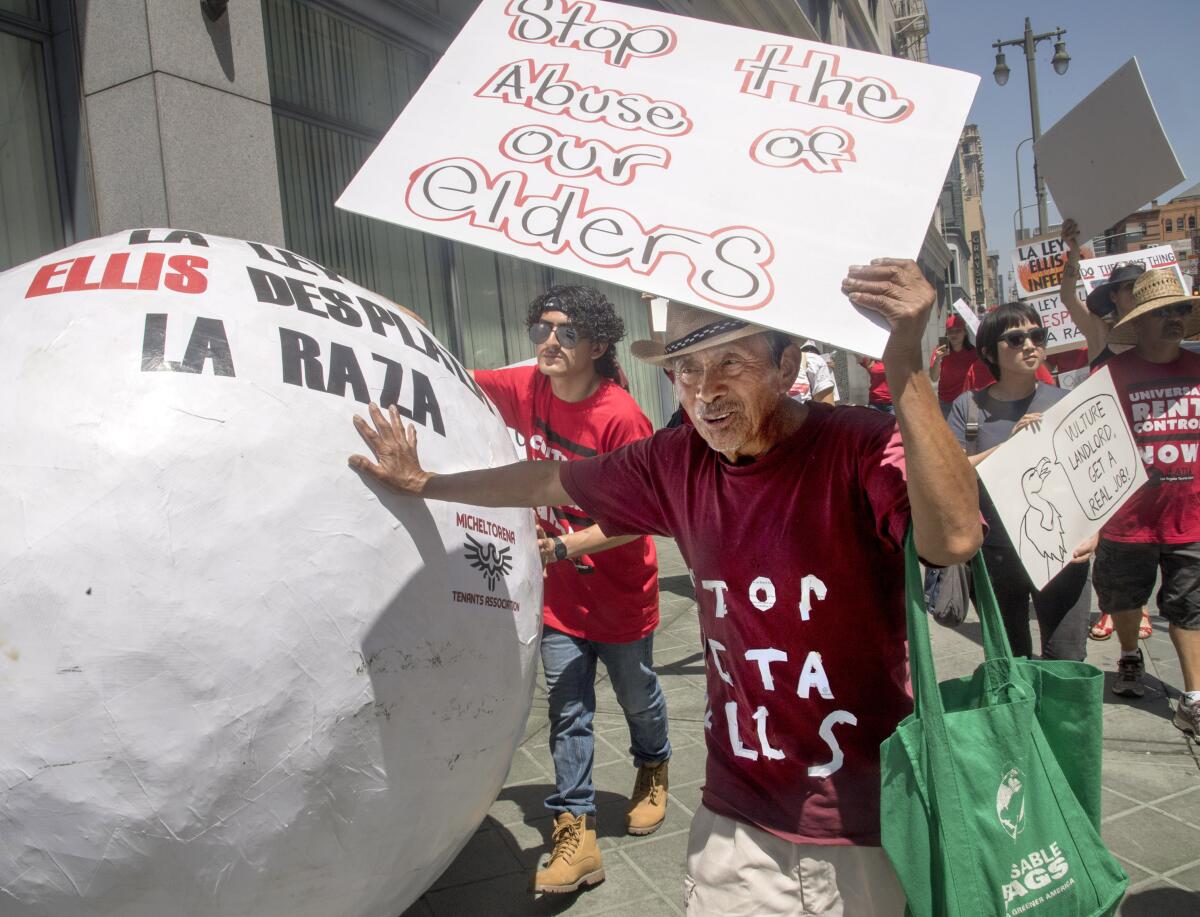 Mario Canel, 73, pushes a papier-mache ball through the streets of downtown L.A. as he protests his eviction