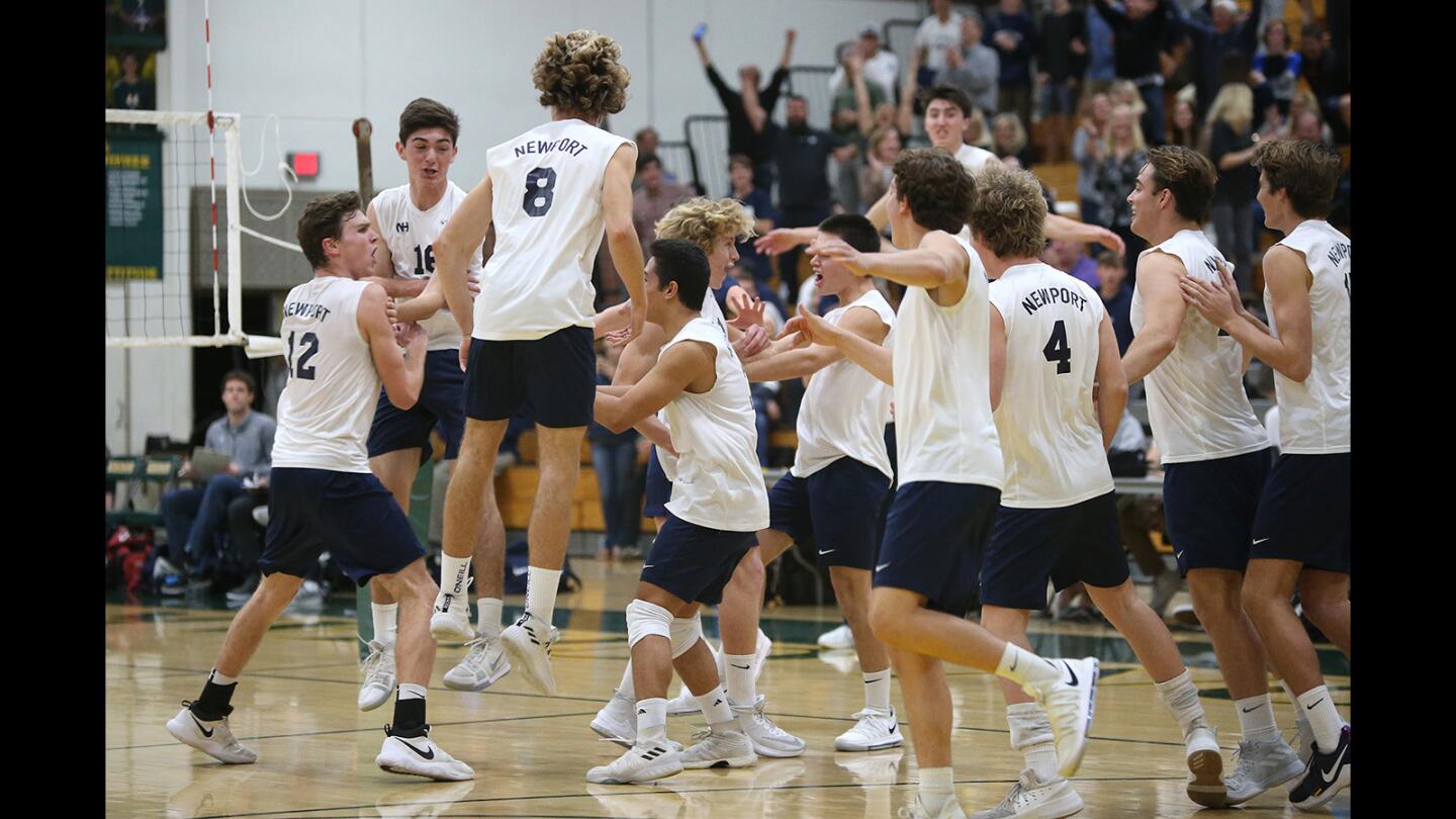 Newport Harbor players run onto the court after defeating Corona Del Mar during "Battle of the Bay" final of the Orange County Championships volleyball tournament at Edison High on Monday.