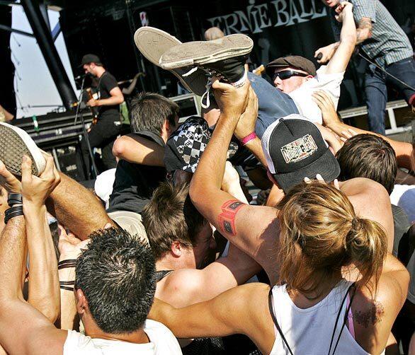 Music fans grab the legs of a body surfer as he makes his way to the front during the Warped Tour kickoff on the Fairplex grounds in Pomona on June 20.