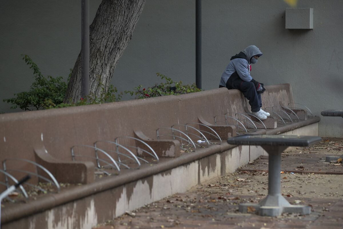 A man sits alone during a visit to Pershing Square in downtown Los Angeles on a rainy afternoon. 