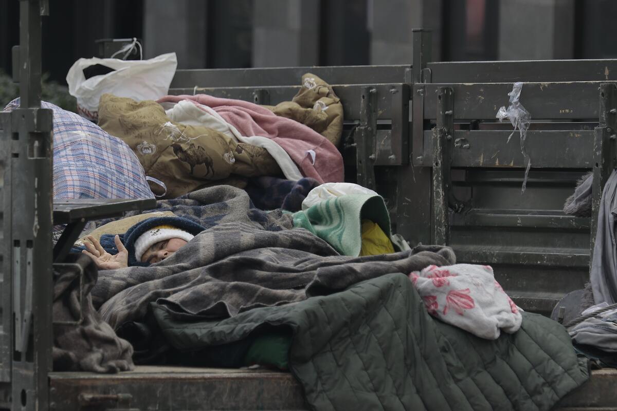 A woman sleeps under blankets in a truck.
