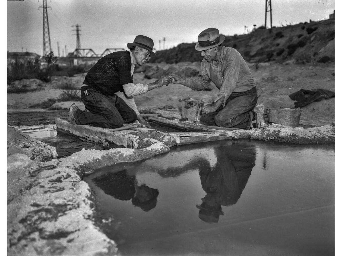 Dec. 11, 1938: Joe Parra, left, and E. Rea examine a gold nugget found in sand in Los Angeles River. The partners are family men with children.